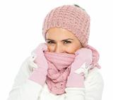 Woman in knit winter clothing closing face with knit scarf