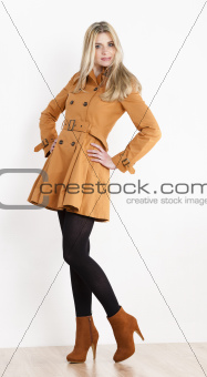 standing woman wearing coat and fashionable brown shoes