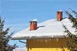 Red chimneys on snowy roof. Piedmont, Italy.