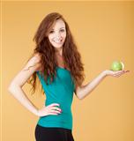 young girl holding a green apple smiling - isolated on yellow