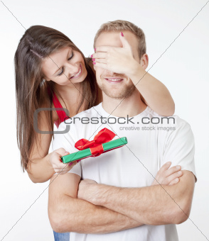 young woman covering her boyfriends eyes to give him a surprise present