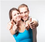 young couple showing both thumbs up smiling- isolated on gray