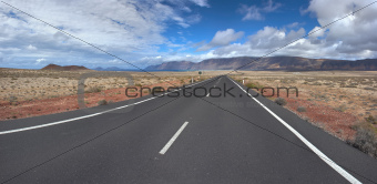 Panorama of the empty road through sandy and volcanic desert, Ca