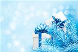 Holiday blue background with gift boxes and tree branches. Vector illustration.