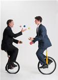 Juggling businessmen riding unicycles