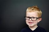 Smart young boy wearing glasses infront of a blackboard