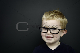 Smart young boy wearing glasses infront of a blackboard