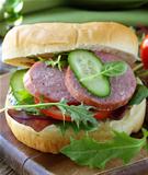 burger with salami and vegetables (cucumbers, tomatoes and lettuce)