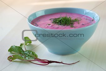 Chlodnik - cold beetroot soup in a bowl on a wooden table.