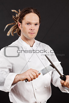 Handsome chef sharpening his knife