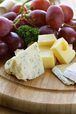 cheeseboard with three kinds of cheese and grapes