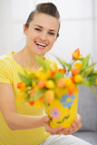 Happy young woman showing bouquet of tulips in bucket