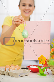 Closeup on blank pink paper sheet with Easter egg holding by wom