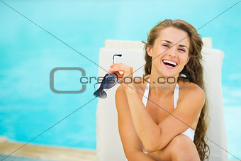 Portrait of happy young woman in swimsuit relaxing poolside
