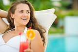 Smiling young woman in swimsuit with cocktail looking on copy sp
