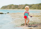 Baby playing with pail on sea shore