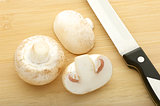 champignons and knife on bamboo cutting board