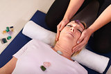 Young therapist arranging crystals on female client for reiki th