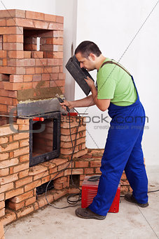 Worker installing door to a masonry heater