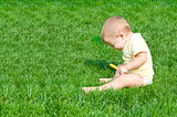 Pretty little boy sneezes sitting on a grass