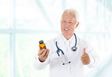 Thumb up Asian doctor holding bottle pills