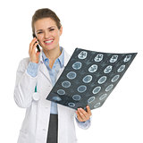 Smiling medical doctor woman speaking mobile phone and holding M
