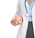 Closeup on medical doctor holding piggy bank