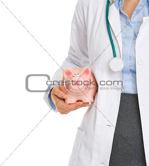 Closeup on medical doctor holding piggy bank
