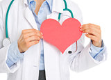 Closeup on medical doctor holding paper heart