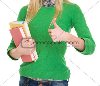 Closeup on student girl with books showing thumbs up