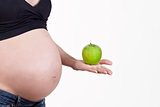 Pregnant woman's belly with and hand handing of green apple on white background