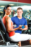 woman and Personal Trainer in gym with dumbbells