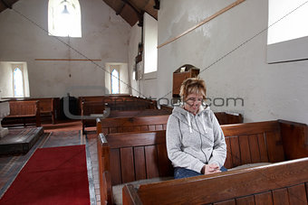 A woman sitting in an empty church praying