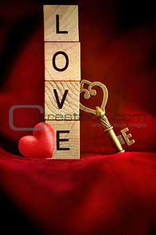 Gold key with wooden block letters that spell the word love