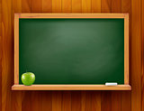 Blackboard with green apple on wooden background