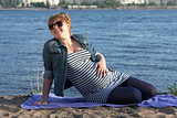 Pregnant woman sitting on the river coast