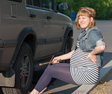 Pregnant Woman with a Wheel Brace near Car