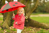 Portrait of smiling baby with red umbrella outdoors