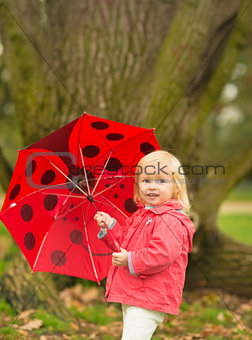 Portrait of happy baby with red umbrella outdoors