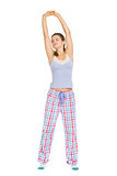 Young woman in pajamas stretching after sleep