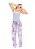 Full length portrait of young woman in pajamas stretching and ya