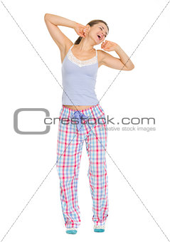 Full length portrait of young woman in pajamas stretching and ya