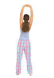Full length portrait of young woman in pajamas stretching. Rear 