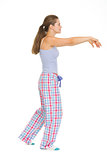 Full length portrait of young woman in pajamas sleep walking