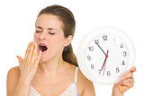 Young woman with clock yawing after sleep