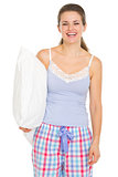 Happy young woman in pajamas holding pillow