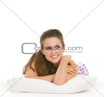 Happy young woman in pajamas laying on pillow and looking on cop