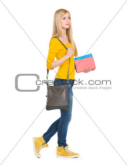 Teenage student girl with books going sideways
