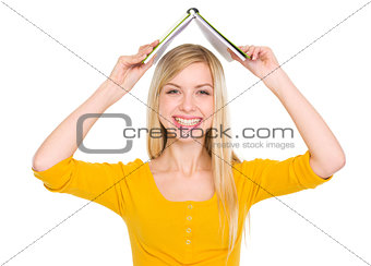 Smiling student girl making roof with book