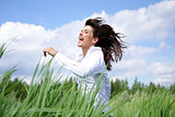 Woman with long hair running outside under blue sky in the field